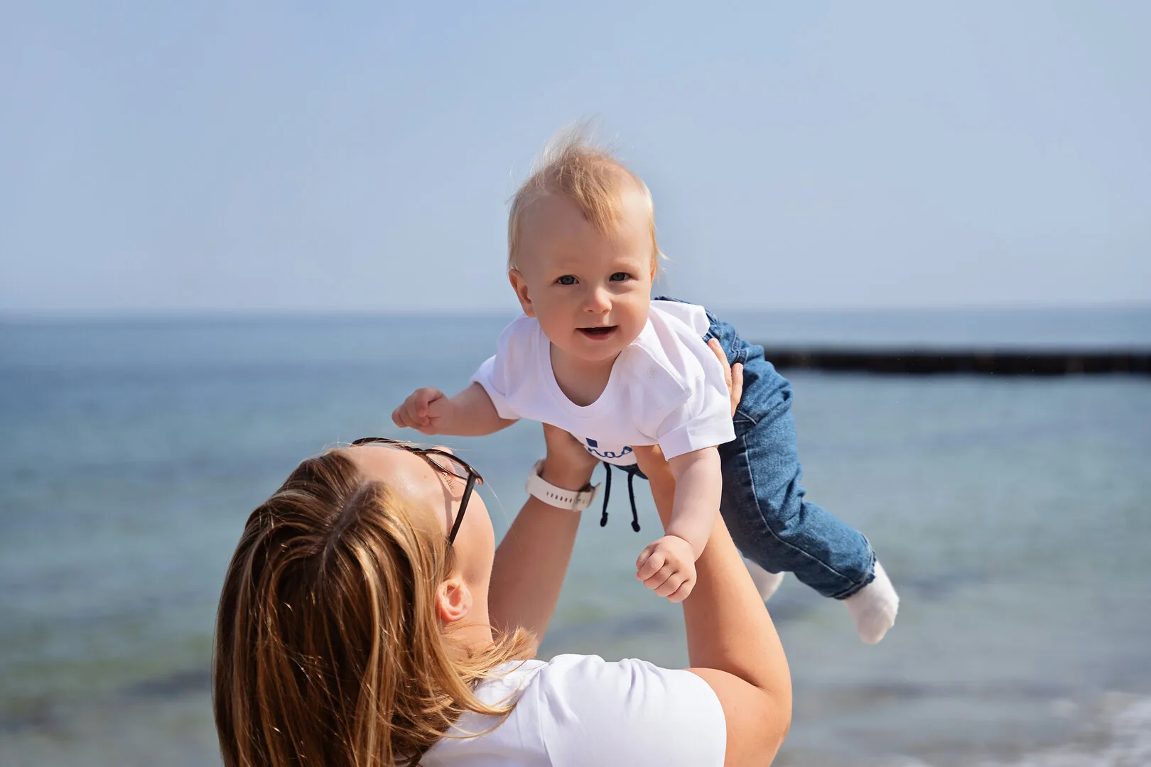 Mama unosząca niemowlę podczas rodzinnej sesji na plaży