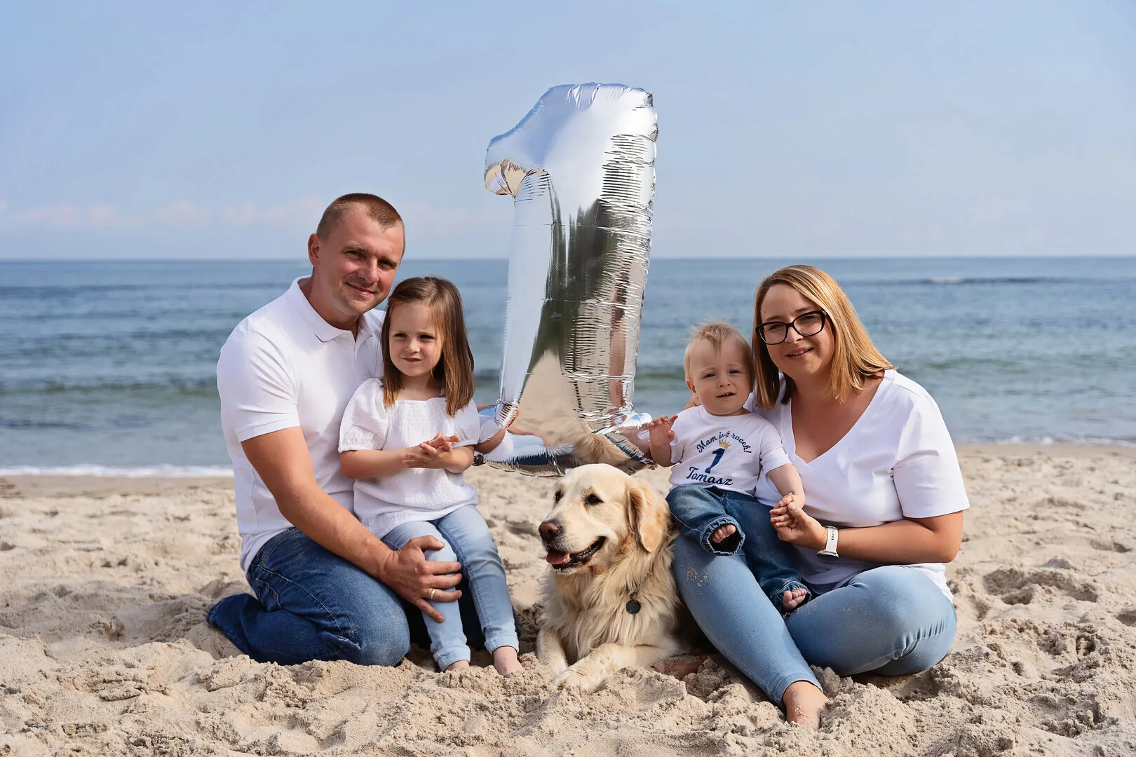 Rodzina siedząca na piasku podczas sesji na Plaży Wschodniej