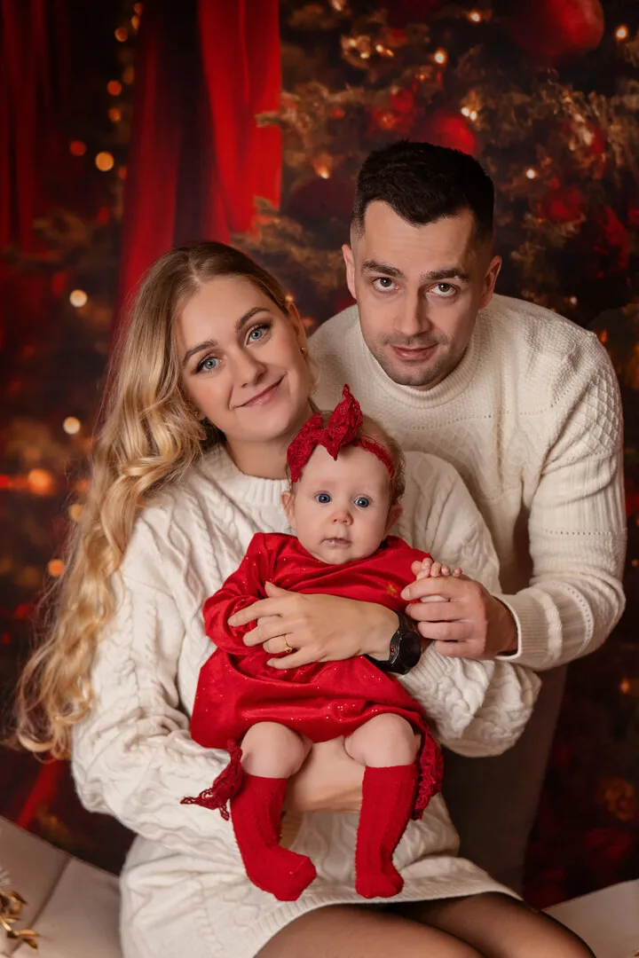 Rodzina z niemowlęciem podczas czerwonej sesji świątecznej