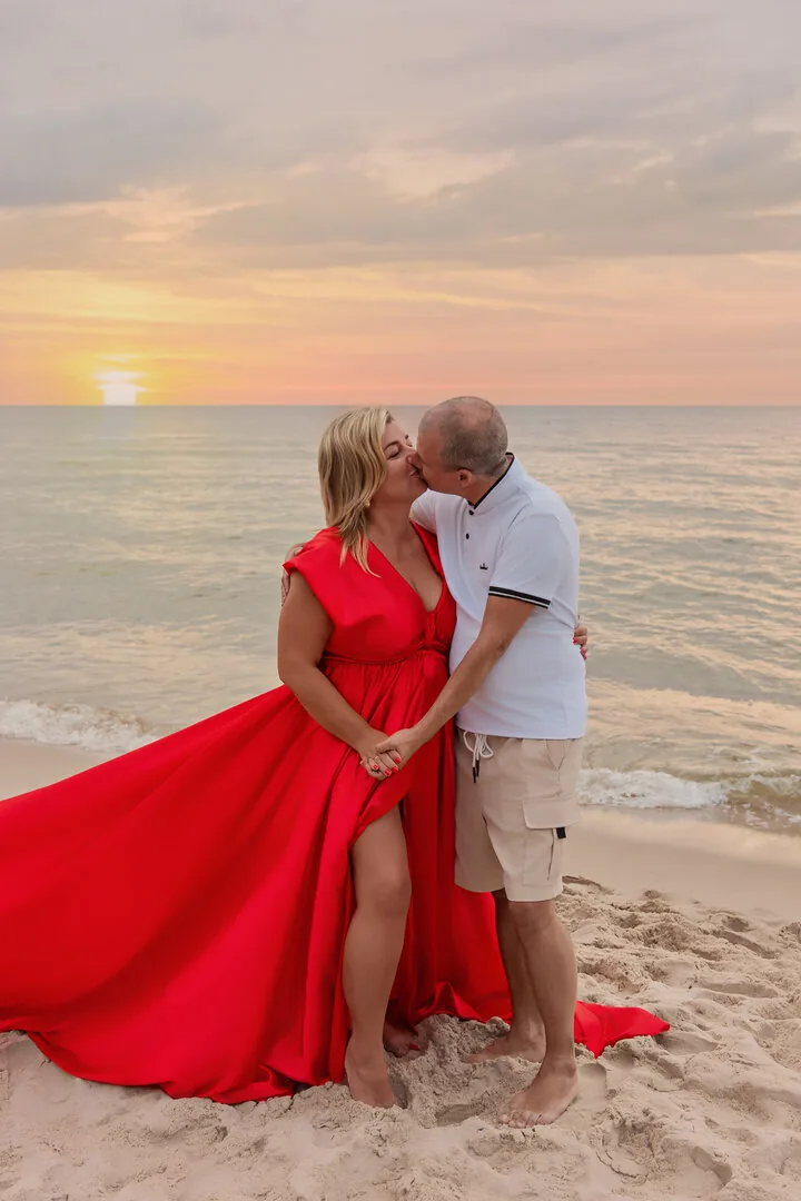 Para na plaży podczas sesji w czerwonej sukni Flying Dress