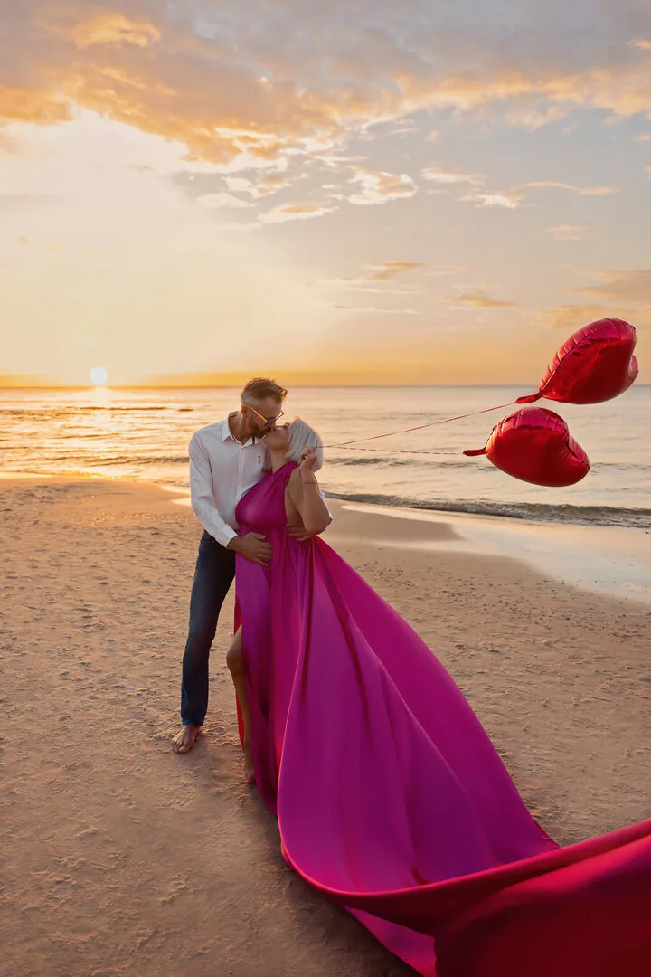 Couple on the beach in a fuchsia Flying Dress at sunset