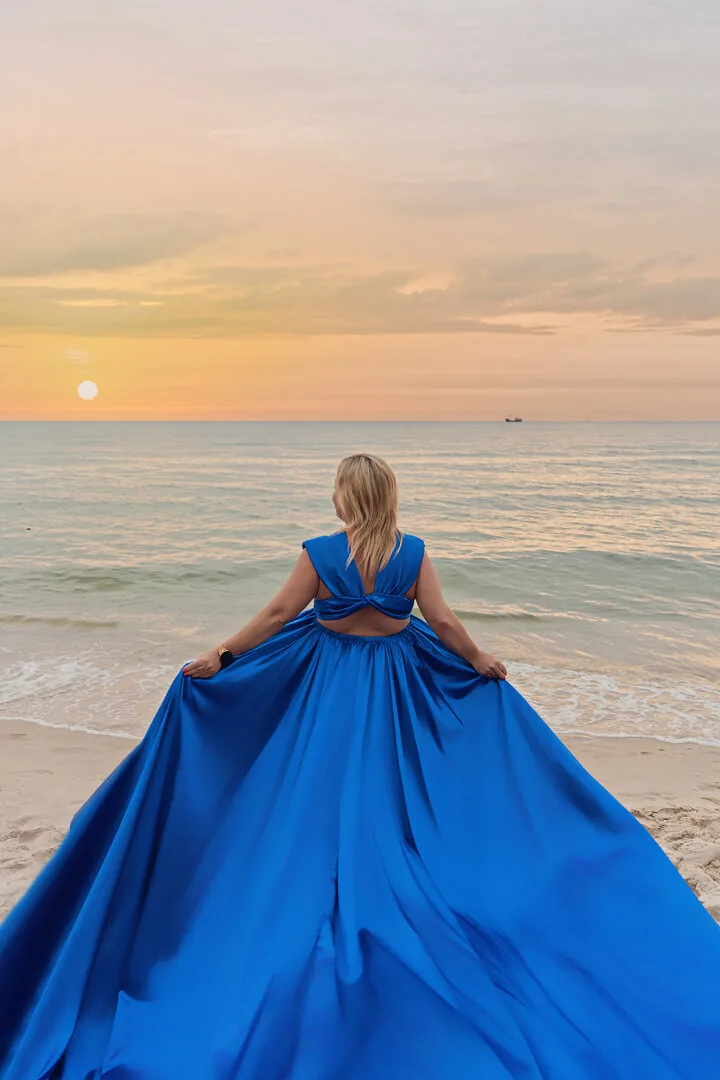 Niebieska suknia Flying Dress sfotografowana od tyłu nad morzem