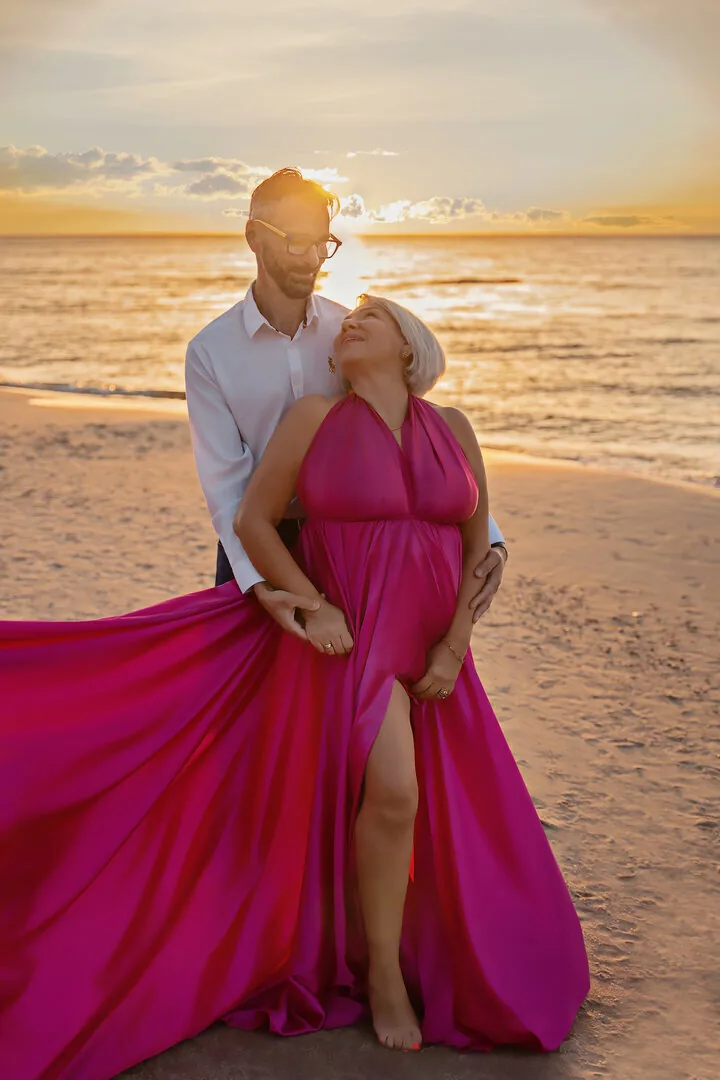Couple on the beach, woman in a fuchsia Flying Dress