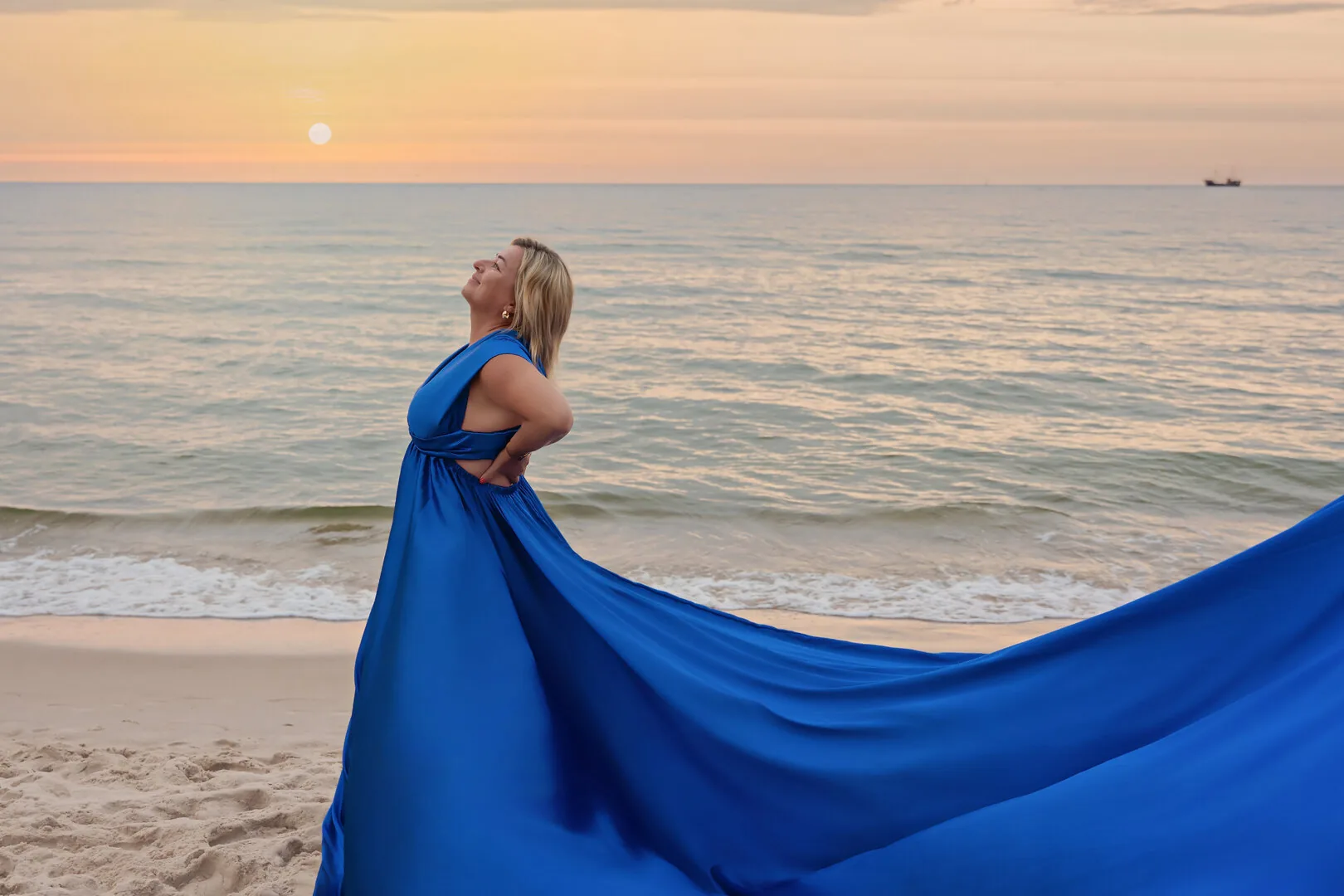 Przyszła mama z trenem niebieskiej sukni Flying Dress na plaży