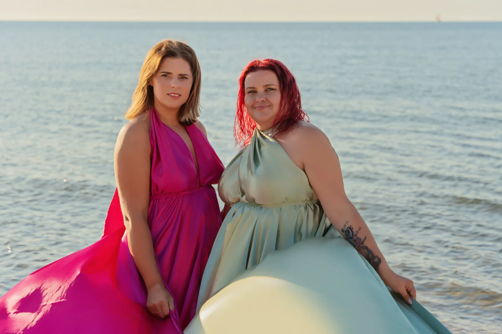 Two women posing in colourful Flying Dresses beside the sea