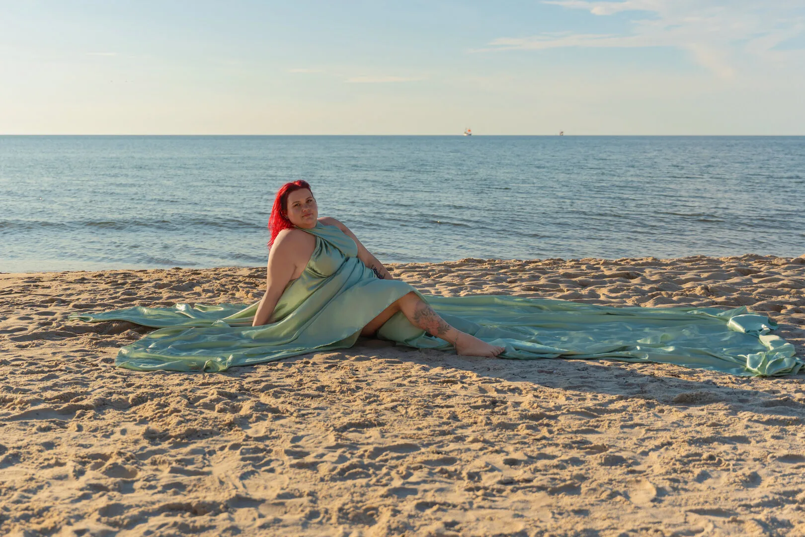 Woman seated on the beach in a sage Flying Dress