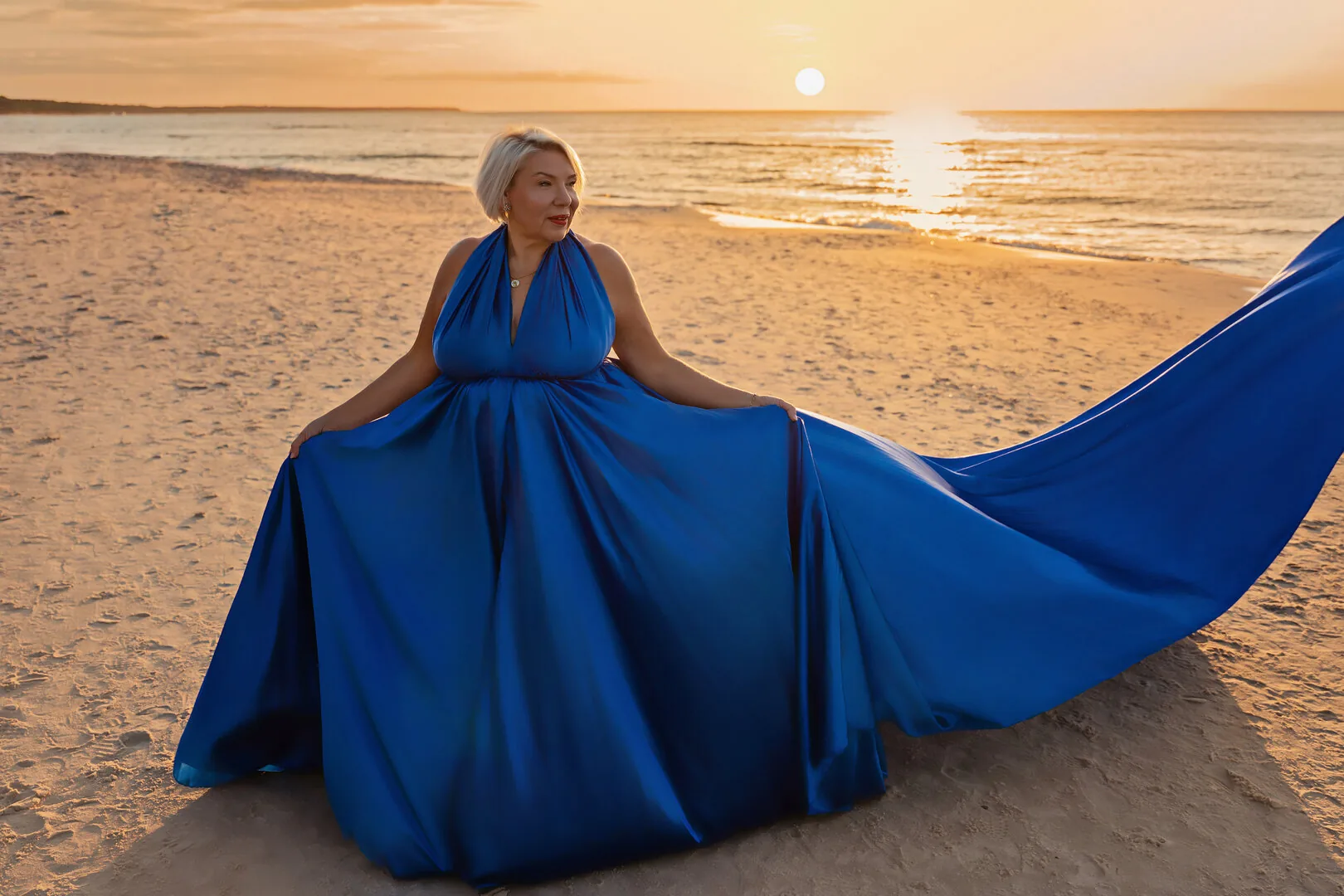 Woman in a blue Flying Dress with a spread train at sunset