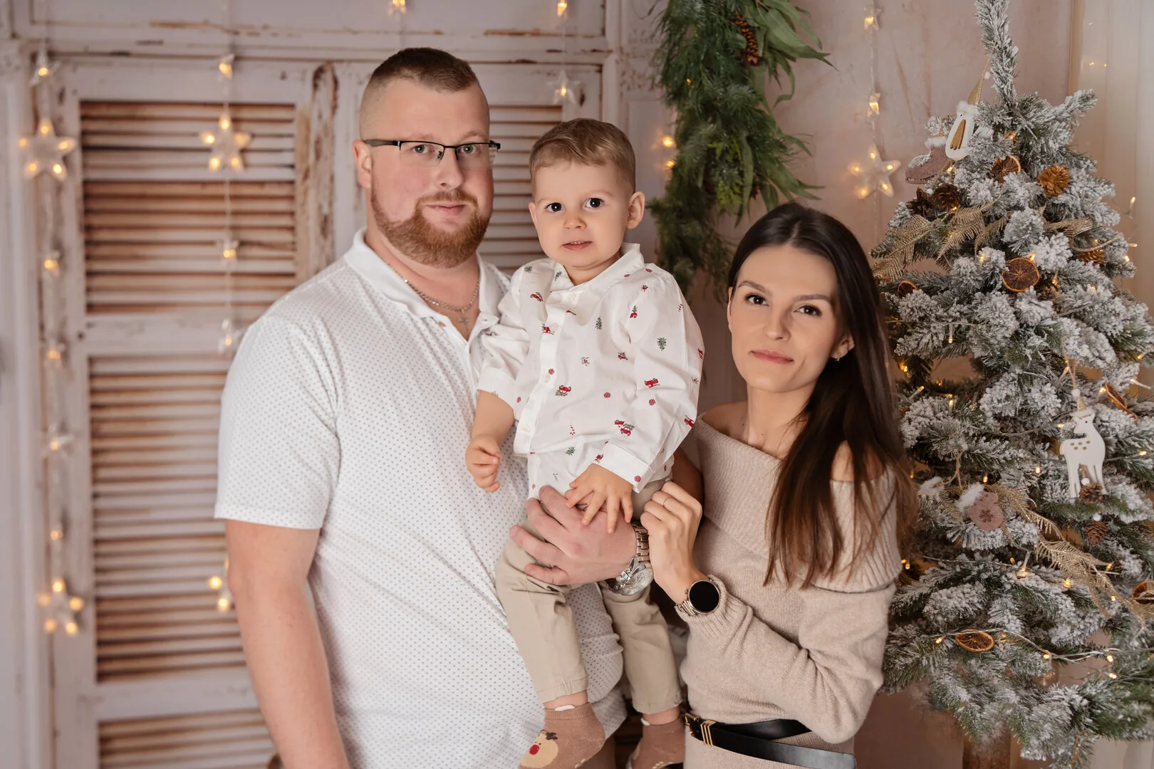 Rodzina z dzieckiem przy jasnej świątecznej choince