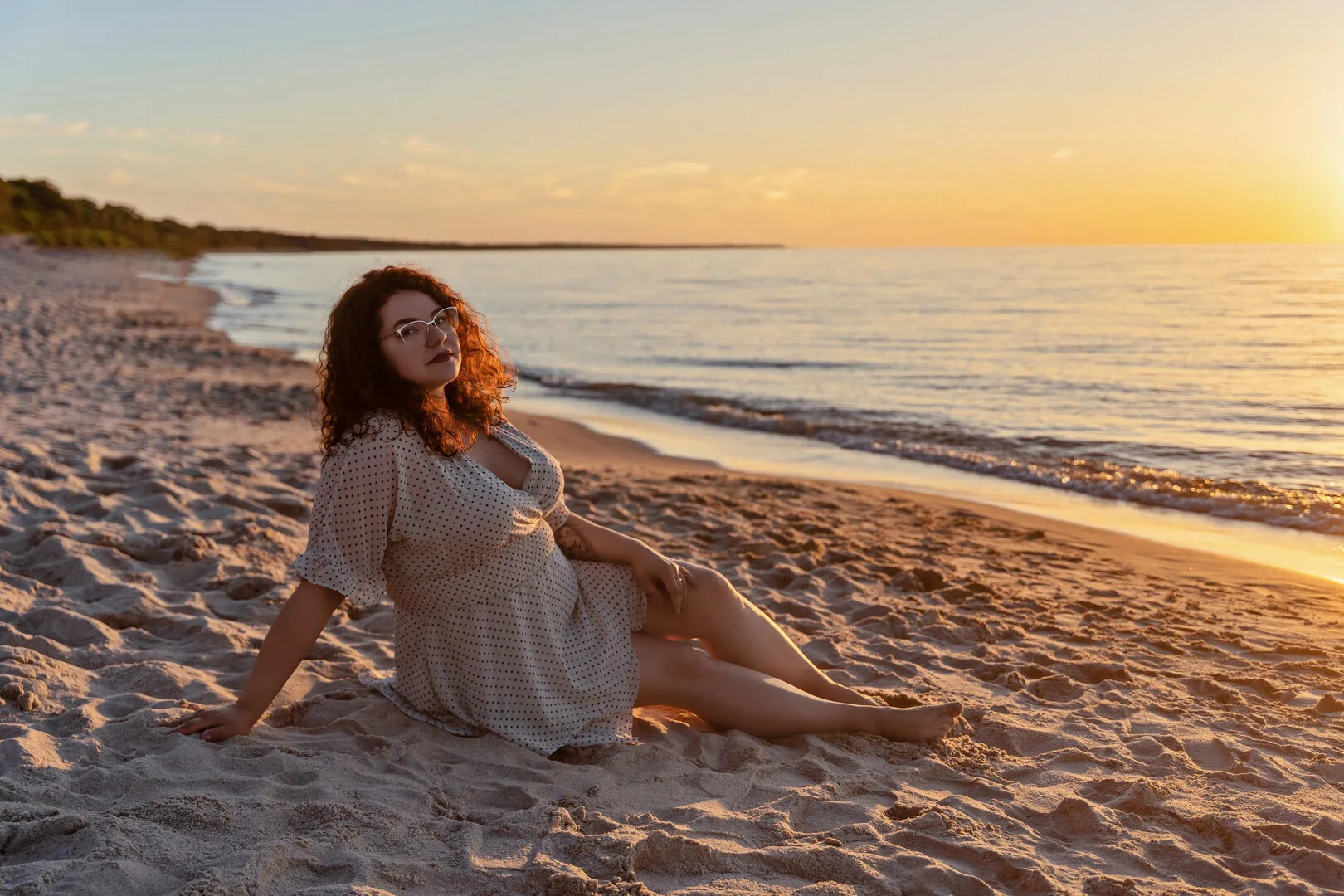 Kobieta w zwiewnej sukience na plaży w złotym świetle