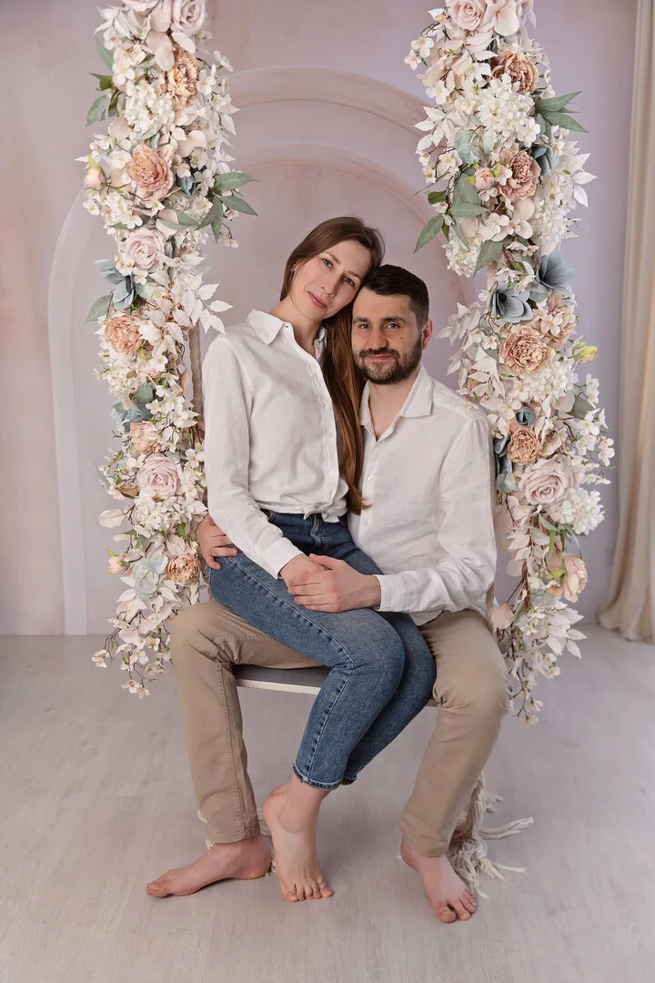 Para siedząca na kwiatowej huśtawce w studio