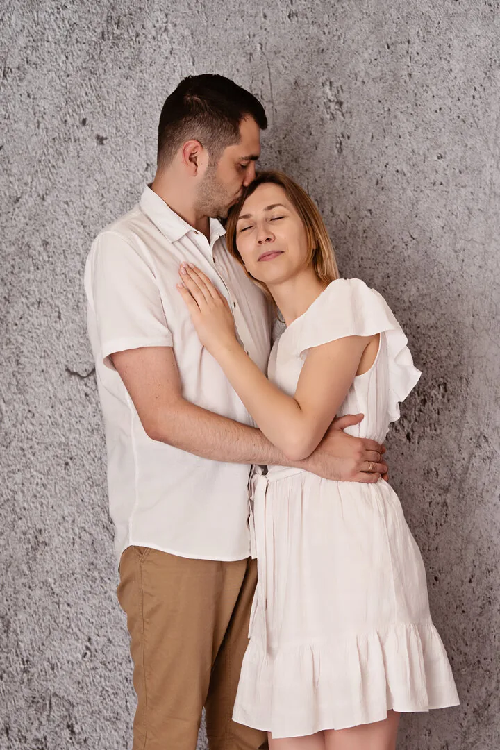 Przytulona para w jasnych ubraniach na szarym tle