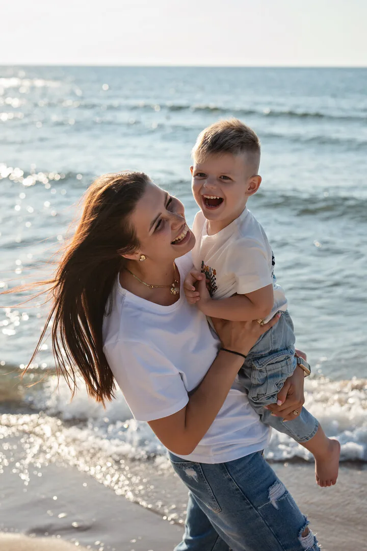 Mama przytulająca małe dziecko przy brzegu morza